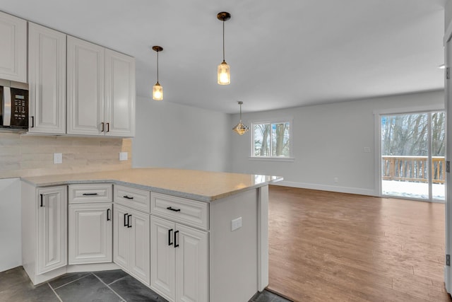 kitchen featuring white cabinetry, decorative backsplash, pendant lighting, and kitchen peninsula