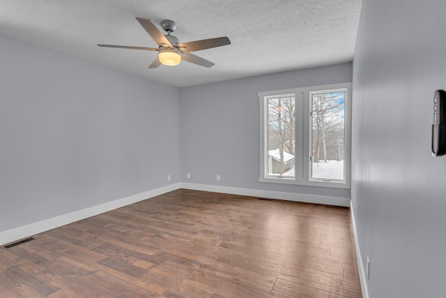 spare room featuring ceiling fan, dark wood-type flooring, and a textured ceiling