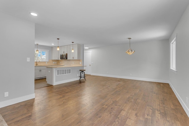 unfurnished living room with wood-type flooring, sink, and a wealth of natural light