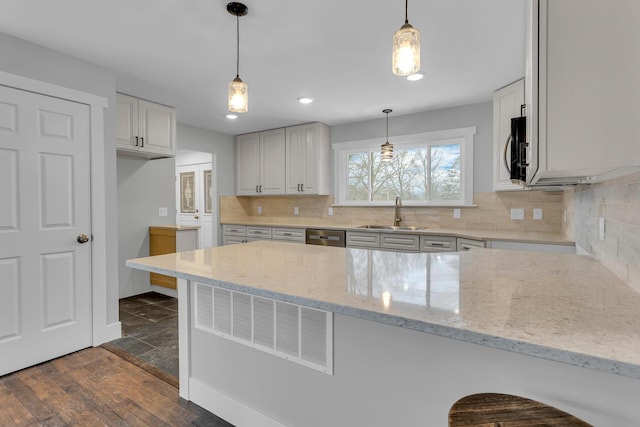 kitchen with sink, hanging light fixtures, light stone countertops, a kitchen bar, and kitchen peninsula