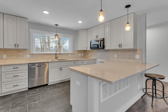 kitchen featuring appliances with stainless steel finishes, sink, white cabinets, a kitchen breakfast bar, and kitchen peninsula