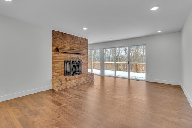 unfurnished living room with a brick fireplace and light wood-type flooring