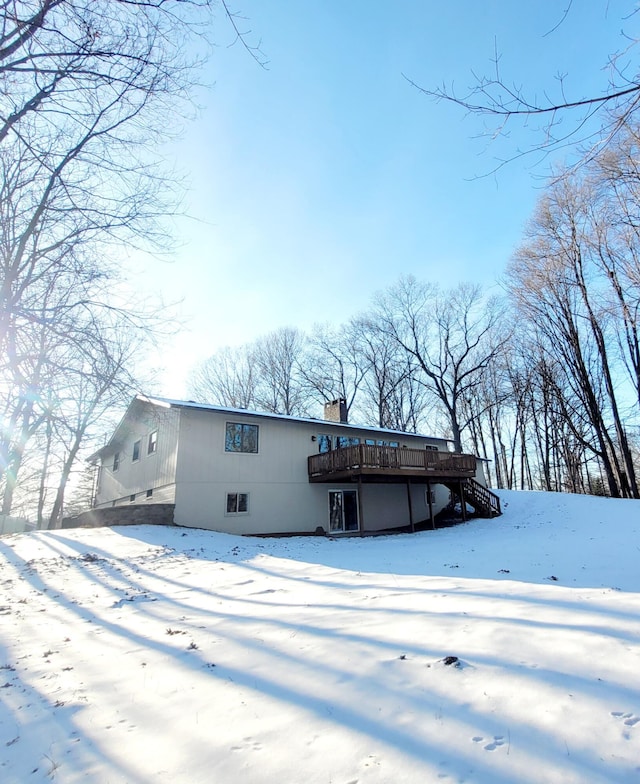 snow covered back of property featuring a deck