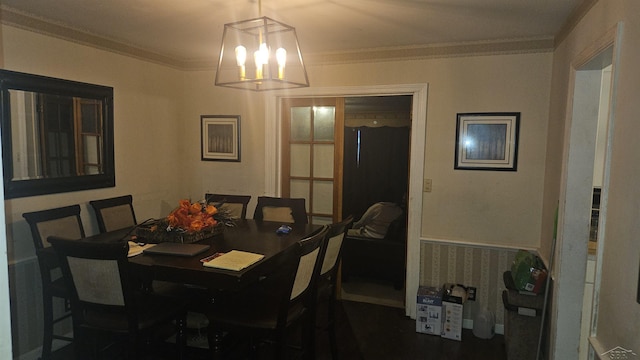 dining space with a chandelier, a wainscoted wall, and crown molding