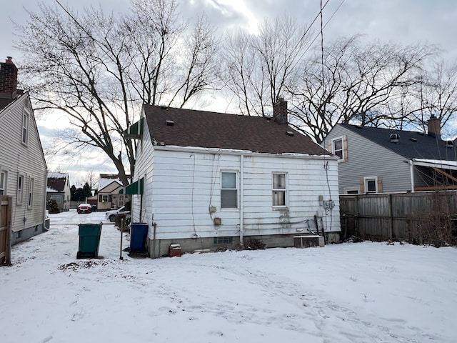 snow covered house featuring central AC unit