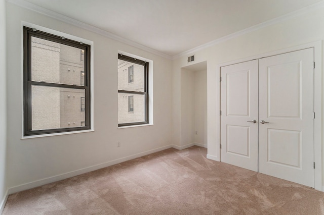 unfurnished bedroom with crown molding, light colored carpet, and a closet