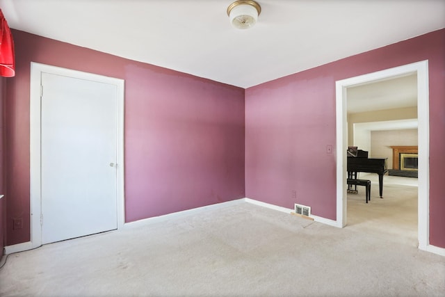 carpeted empty room with a fireplace