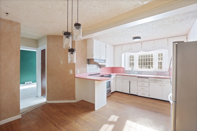 kitchen featuring sink, light hardwood / wood-style flooring, appliances with stainless steel finishes, white cabinetry, and decorative light fixtures