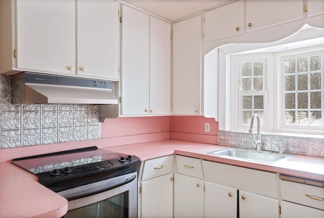 kitchen with tasteful backsplash, stainless steel electric stove, sink, and white cabinets