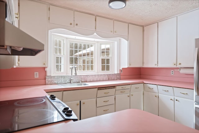 kitchen featuring stove, sink, a textured ceiling, and white cabinets