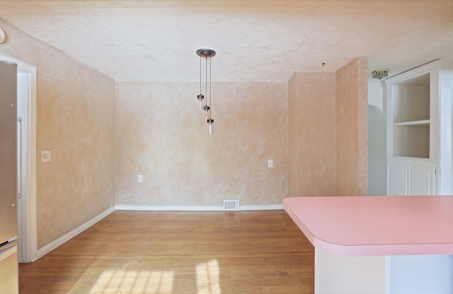 interior space featuring built in shelves, hardwood / wood-style floors, and a textured ceiling