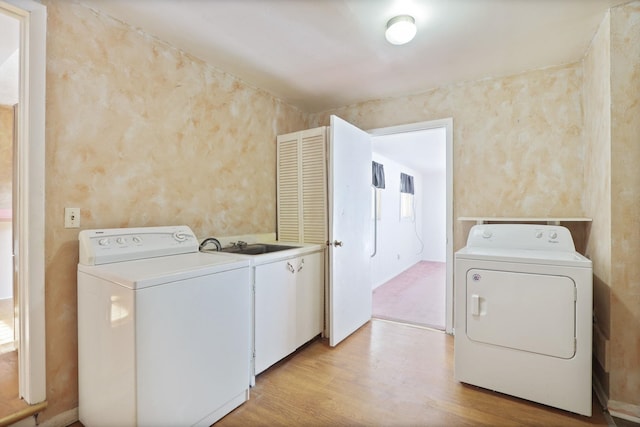 laundry area with sink, light hardwood / wood-style flooring, and washing machine and clothes dryer