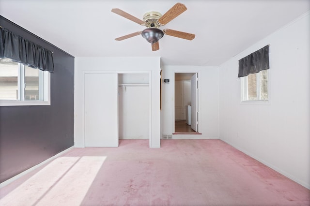 unfurnished bedroom featuring multiple windows, carpet flooring, ceiling fan, and a closet