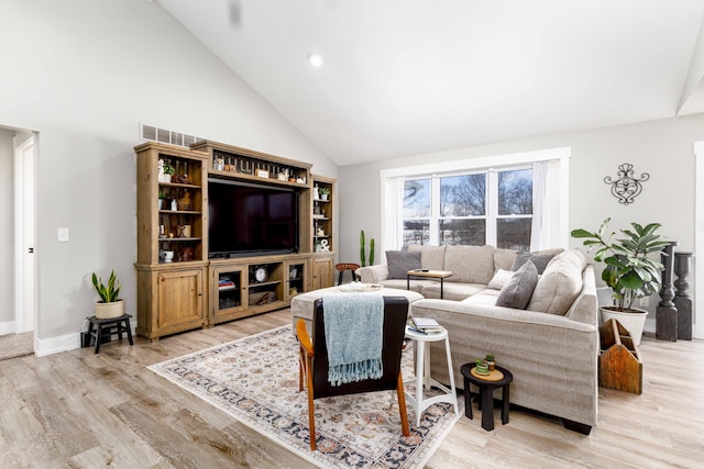 living room with high vaulted ceiling and light wood-type flooring