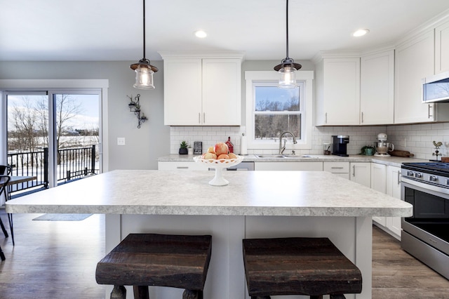 kitchen with hanging light fixtures, stainless steel gas range, sink, and a breakfast bar