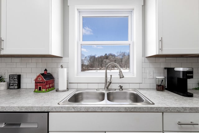 kitchen featuring tasteful backsplash, sink, stainless steel dishwasher, and white cabinets