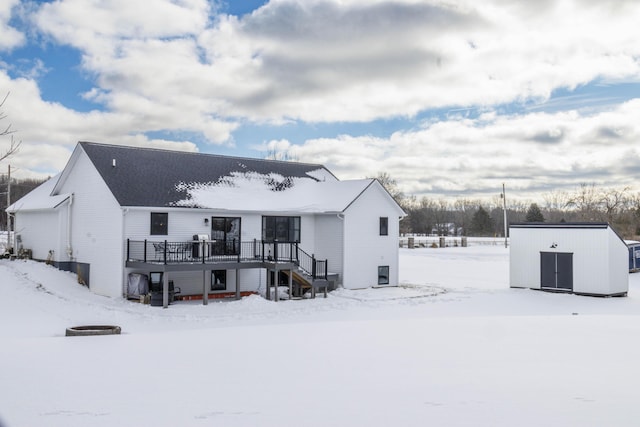 snow covered rear of property featuring a wooden deck and a storage shed