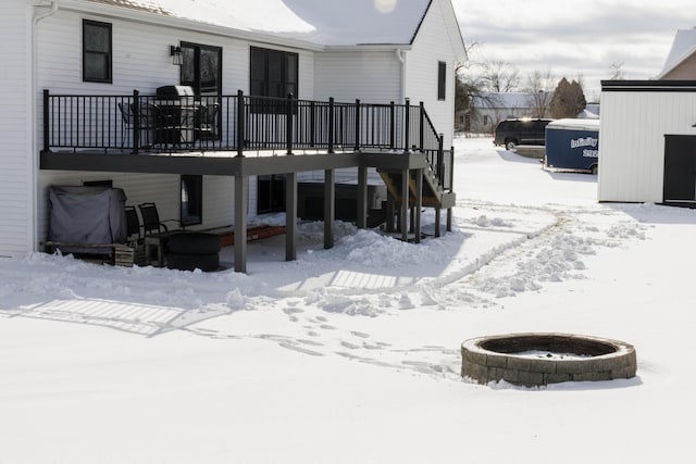 snow covered house featuring a wooden deck and an outdoor fire pit