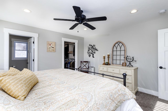 carpeted bedroom with ceiling fan, a walk in closet, and a closet