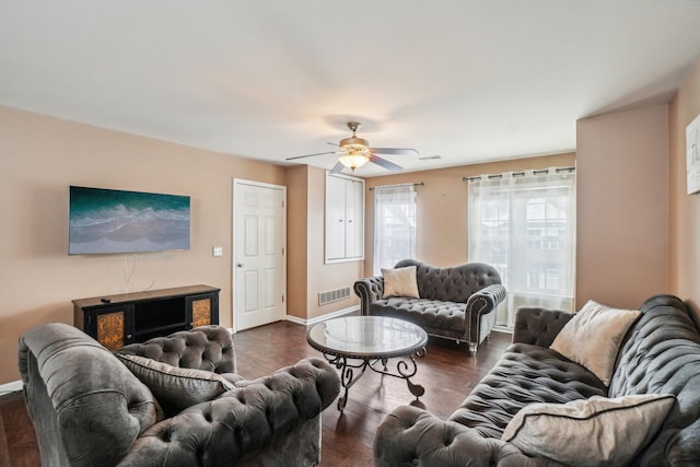 living room featuring a ceiling fan, visible vents, baseboards, and dark wood-style flooring