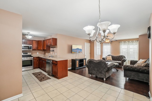 kitchen featuring a peninsula, stainless steel appliances, open floor plan, light countertops, and pendant lighting