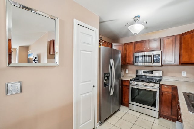 kitchen with stainless steel appliances, brown cabinets, light countertops, and light tile patterned floors