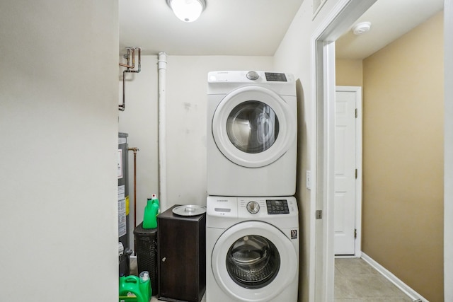 laundry room featuring stacked washer and dryer, laundry area, baseboards, and light tile patterned floors