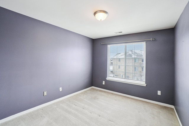 empty room with light colored carpet, visible vents, and baseboards