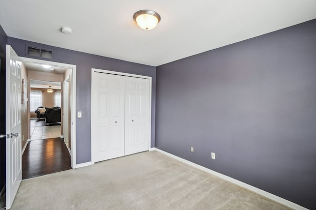 unfurnished bedroom featuring baseboards, visible vents, a closet, and light colored carpet