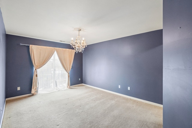 spare room featuring a chandelier, carpet, and baseboards