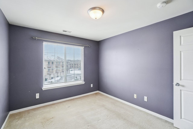 empty room featuring baseboards, visible vents, and light colored carpet