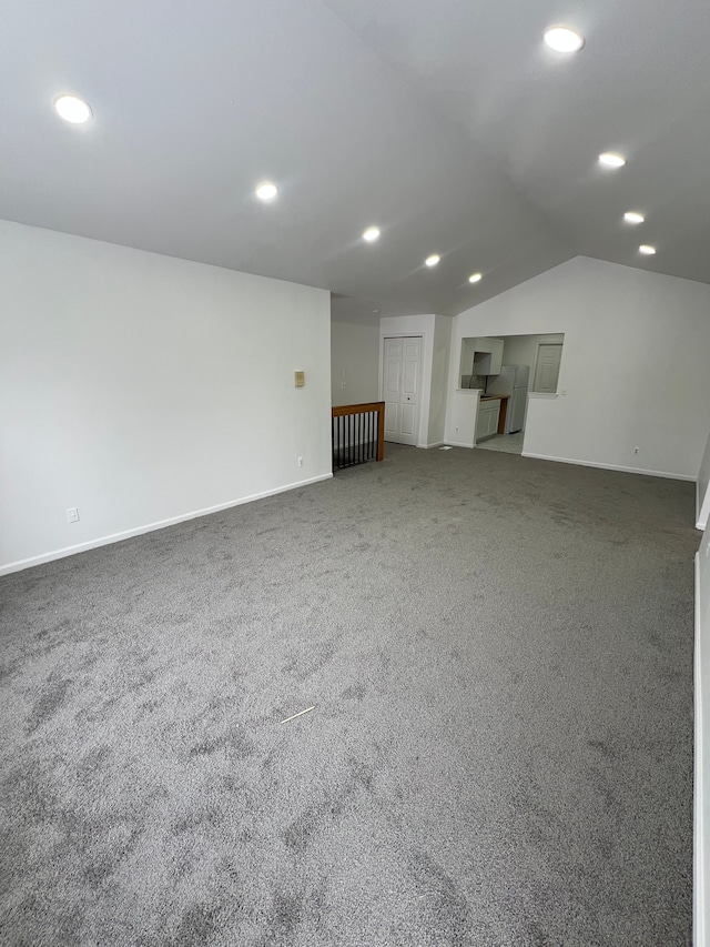 unfurnished living room featuring carpet flooring and vaulted ceiling