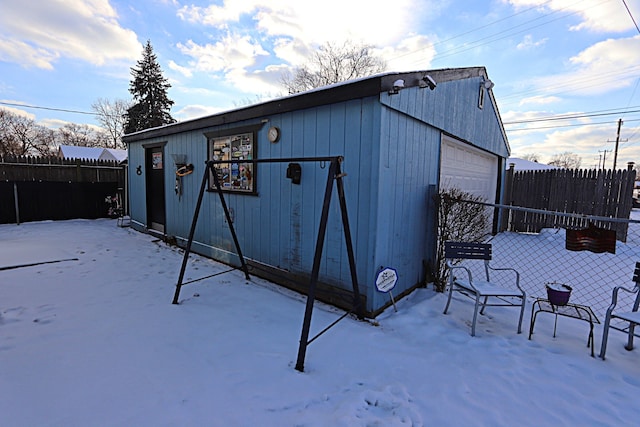 snow covered structure featuring a garage