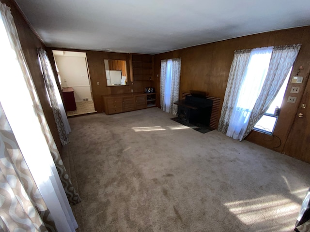 unfurnished living room with carpet floors and wood walls