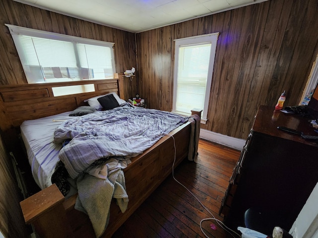 bedroom featuring dark hardwood / wood-style flooring, multiple windows, and wood walls