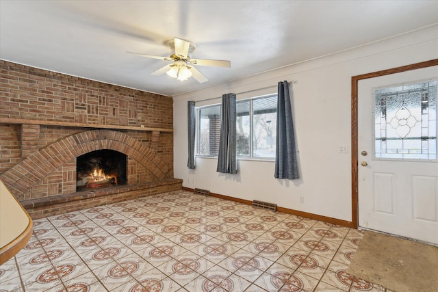 unfurnished living room featuring a brick fireplace and ceiling fan