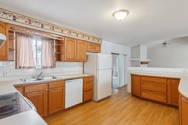 kitchen with sink, light wood-type flooring, backsplash, white appliances, and a textured ceiling