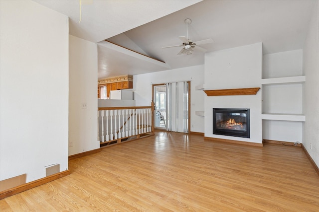 unfurnished living room featuring built in shelves, ceiling fan, vaulted ceiling, and light hardwood / wood-style flooring