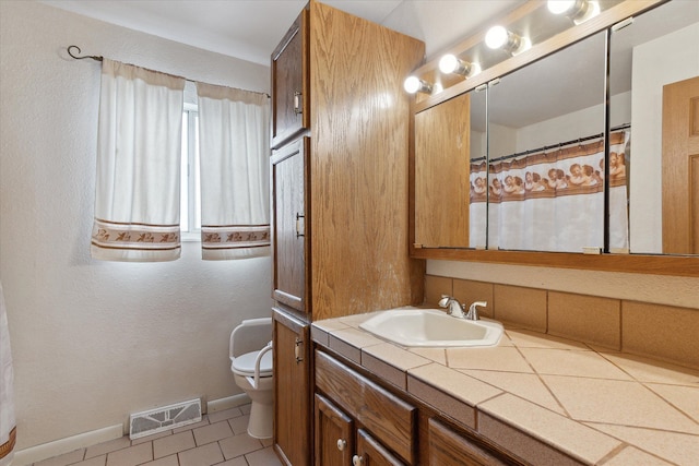 bathroom featuring vanity, toilet, and tile patterned flooring