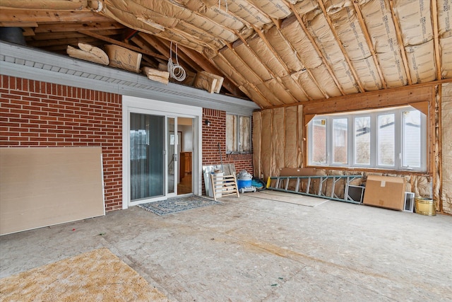 interior space with lofted ceiling and brick wall