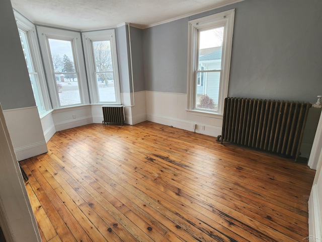 unfurnished room with radiator, light hardwood / wood-style flooring, and ornamental molding