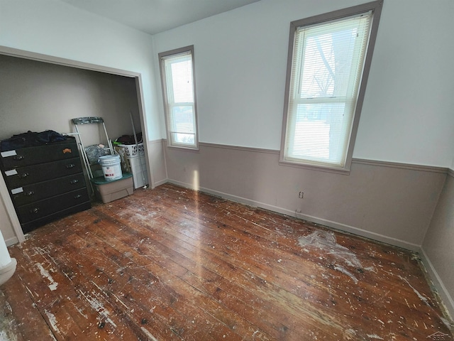 unfurnished bedroom with dark hardwood / wood-style flooring and multiple windows