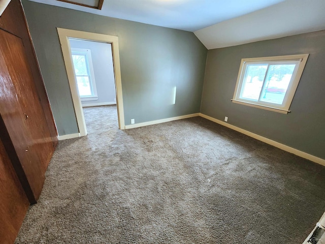 carpeted spare room with lofted ceiling