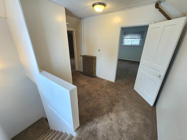 hallway with radiator and dark colored carpet