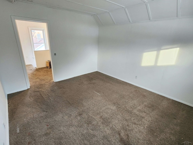 empty room with lofted ceiling and dark carpet