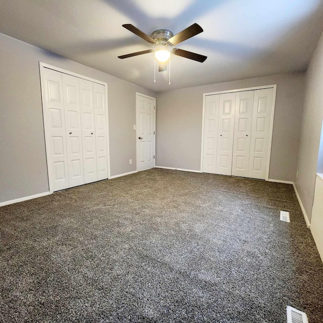 unfurnished bedroom with multiple closets, carpet, and ceiling fan