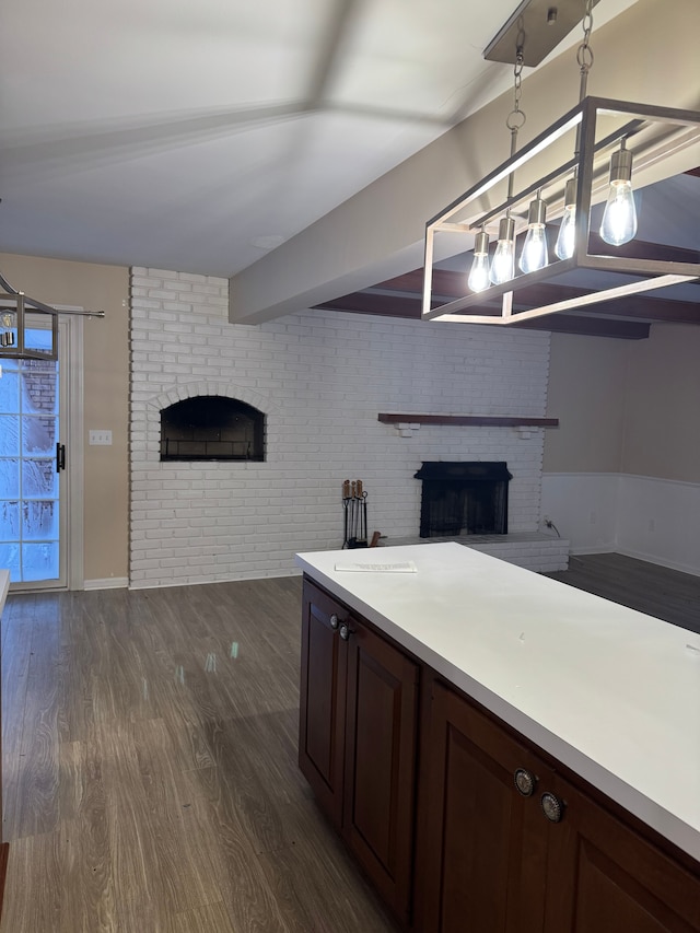 kitchen featuring dark brown cabinets, brick wall, dark hardwood / wood-style flooring, a brick fireplace, and decorative light fixtures