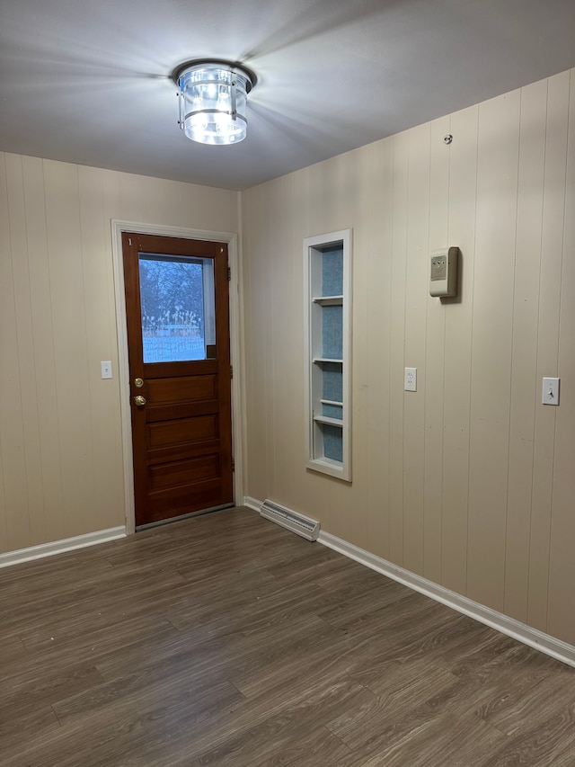 entryway with dark hardwood / wood-style floors, built in features, and wood walls