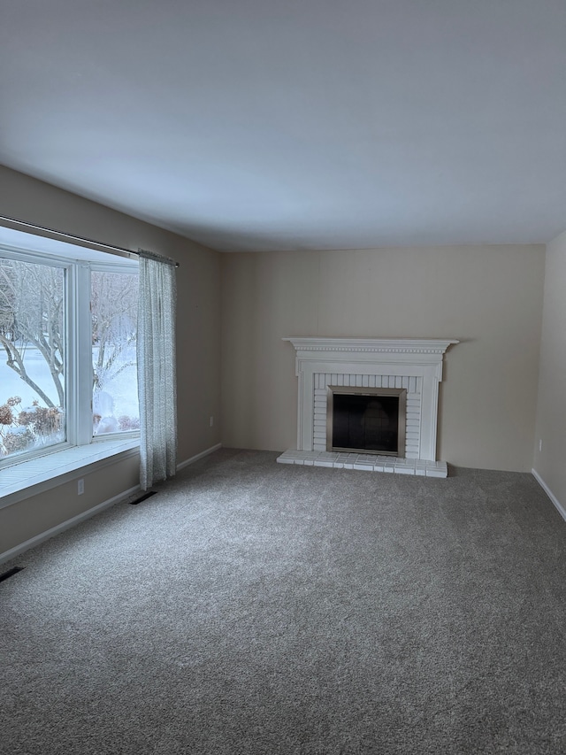 unfurnished living room with a brick fireplace and carpet