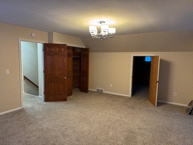 interior space featuring vaulted ceiling, light carpet, and a notable chandelier